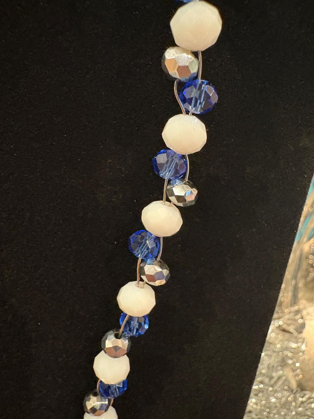 Necklace with white, blue, and silver beads on a black background