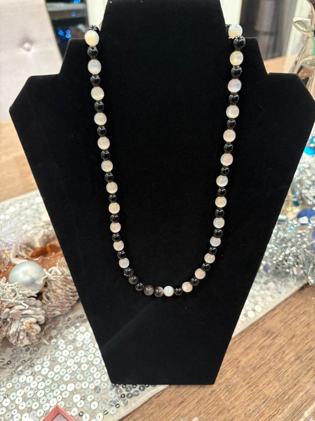 Necklace with black and white beads on a black stand